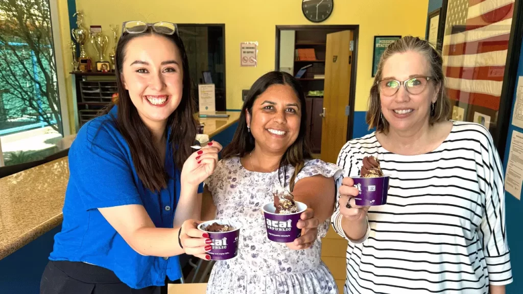 three women smiling and tasting açaí
